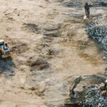 Three yellow excavators near front end loader